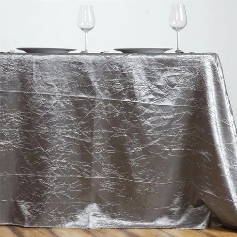 A table with a silver tablecloth and two wine glasses on it.