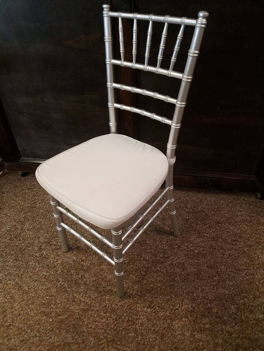 A silver chiavari chair with a white cushion is sitting on a carpet.