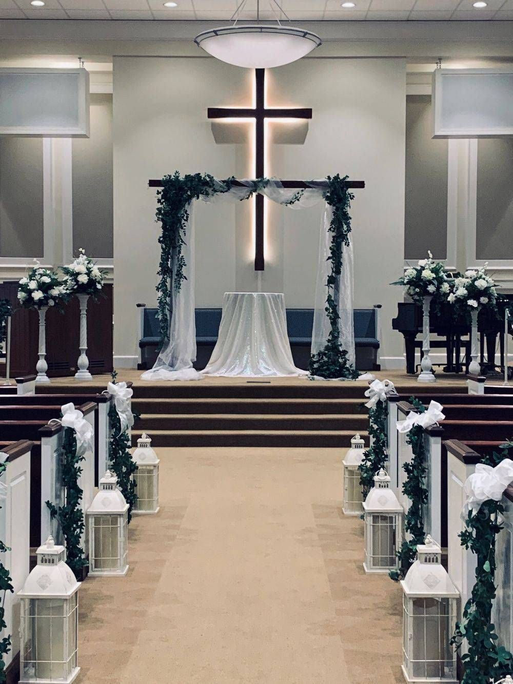 A church decorated for a wedding ceremony with a cross on the wall.