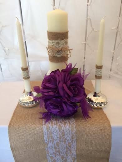 A candle is sitting on top of a table with purple flowers.