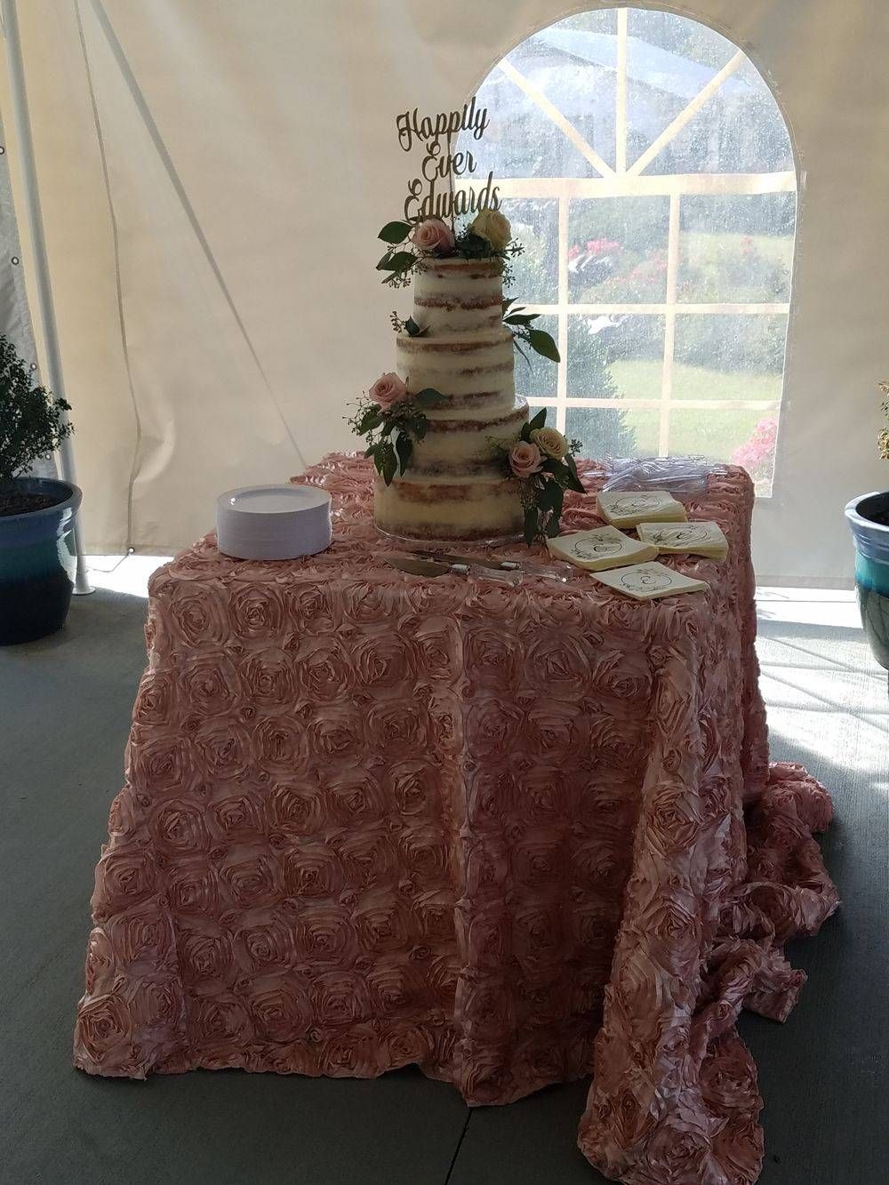 A wedding cake is sitting on top of a table under a tent.