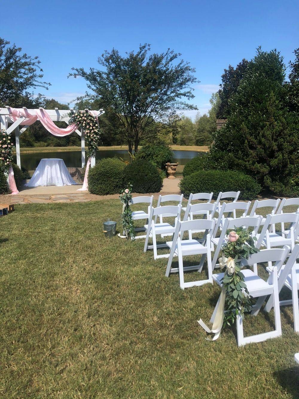 A row of white folding chairs sitting on top of a lush green field.