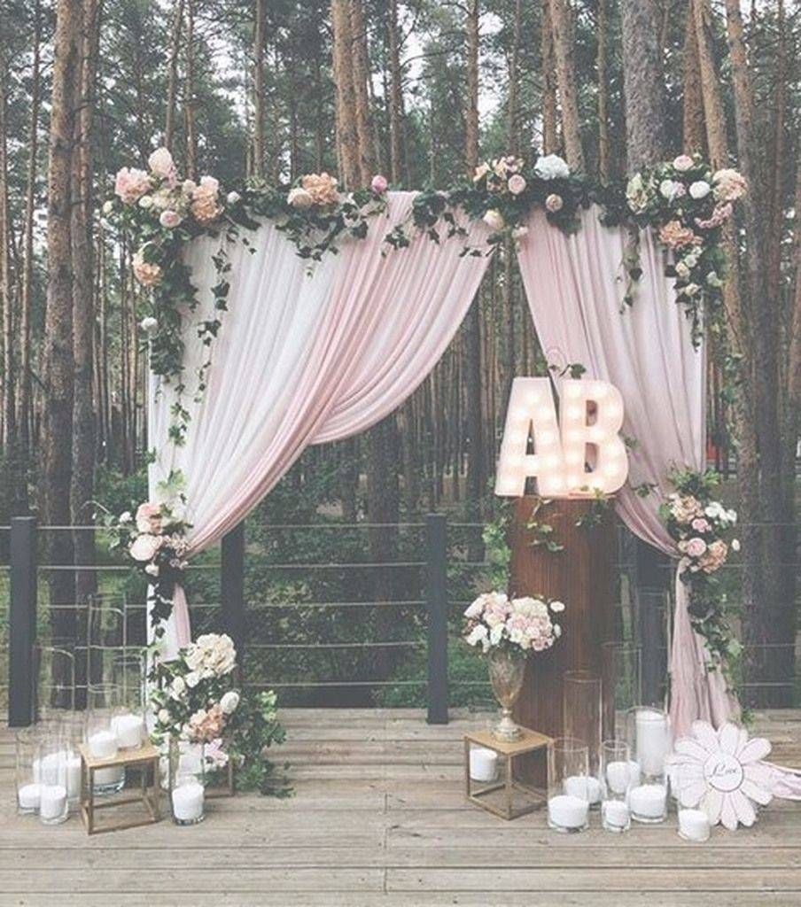 A wedding arch decorated with flowers and candles in the woods.