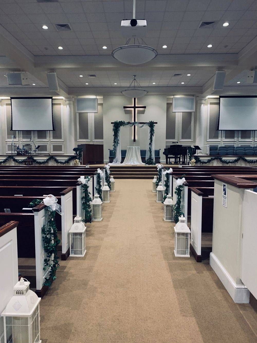 A church is decorated for a wedding ceremony with a cross on the altar.