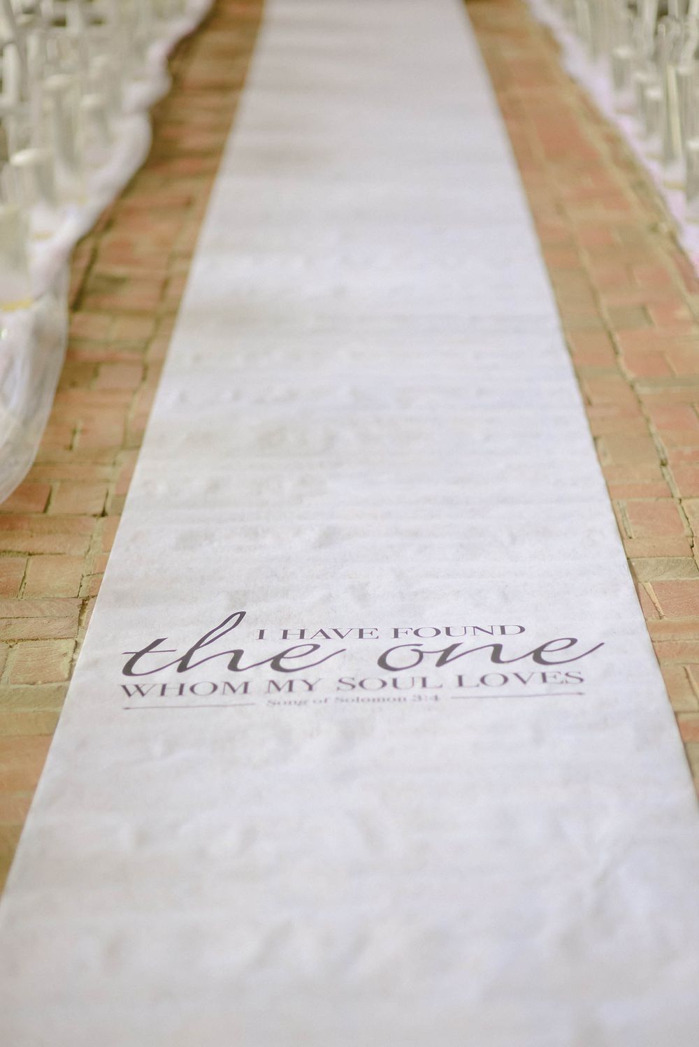 A white aisle runner with the words `` i have found the one whom my soul loves '' on it.