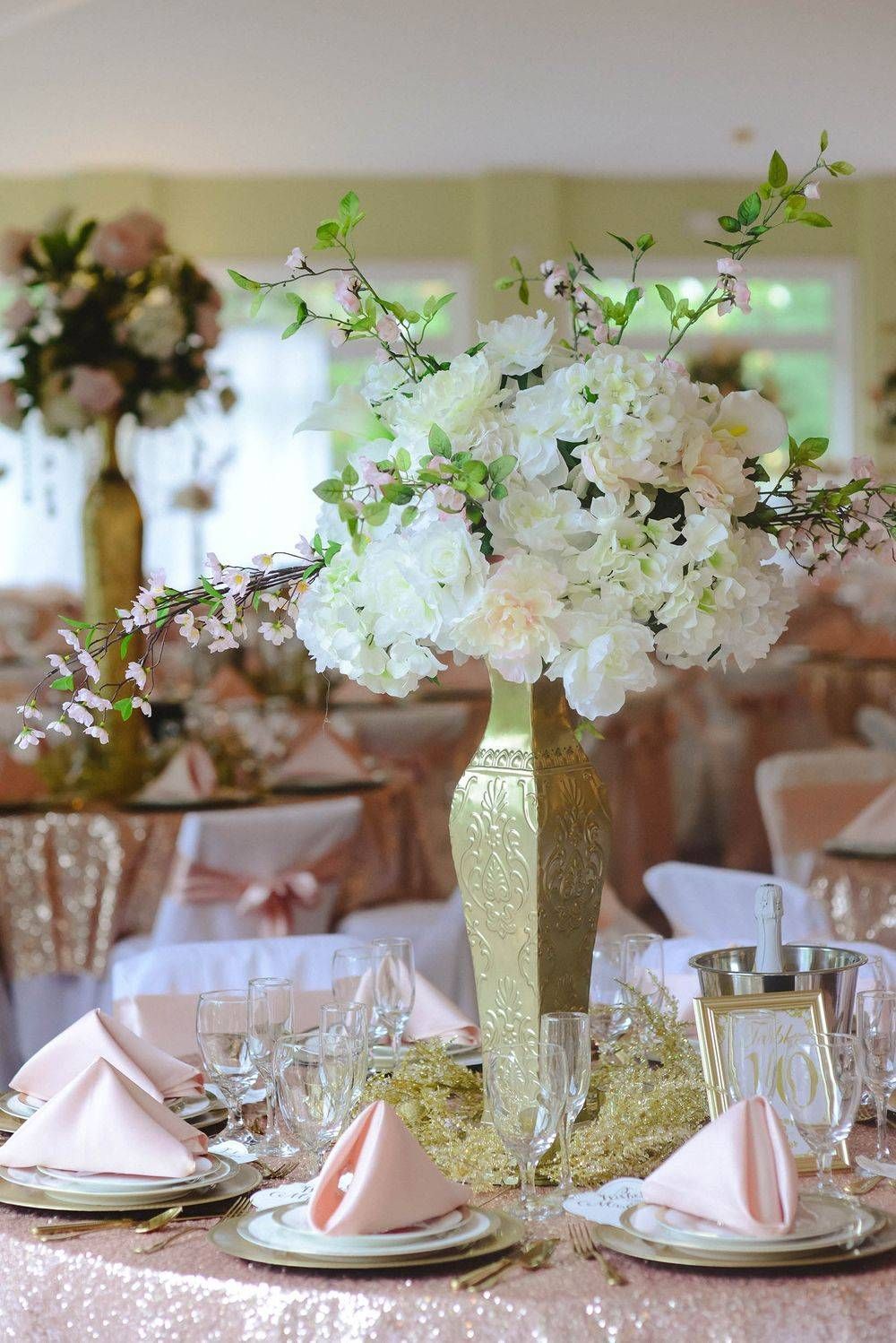 A table set for a wedding reception with a vase filled with flowers on it.