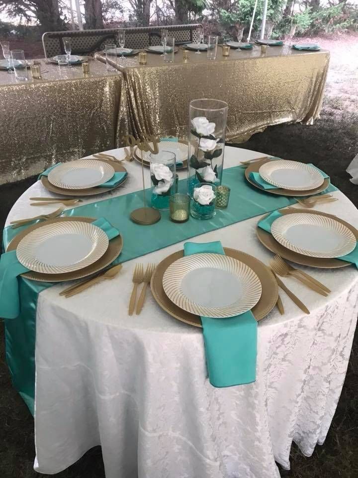 A table with plates , napkins , utensils and a vase of flowers on it.