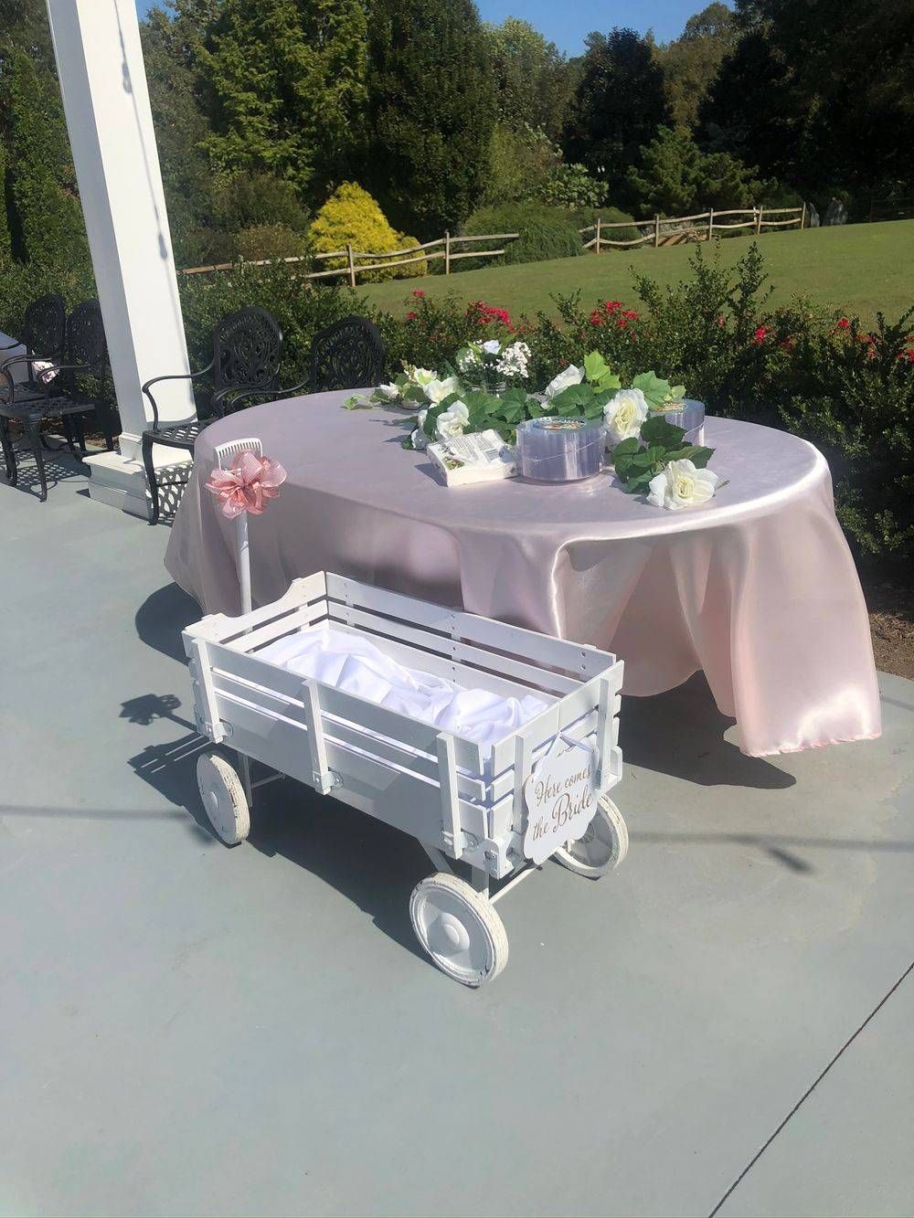 A white wagon is sitting next to a table with flowers on it.