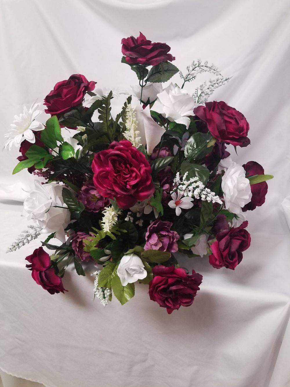 A bouquet of red and white flowers on a white cloth