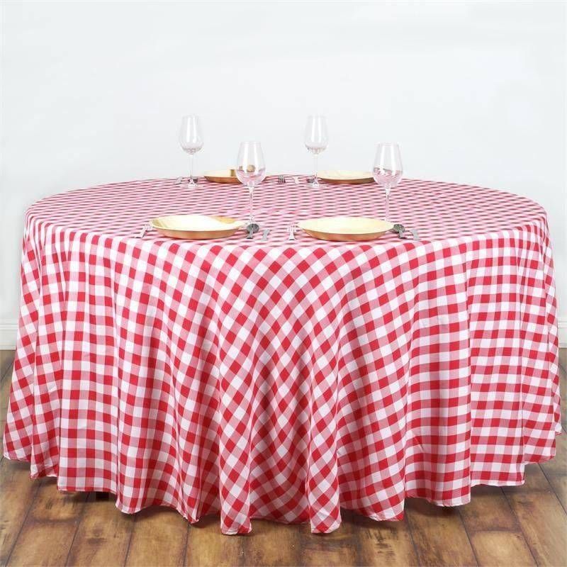 A round table with a red and white checkered tablecloth and plates and glasses on it.
