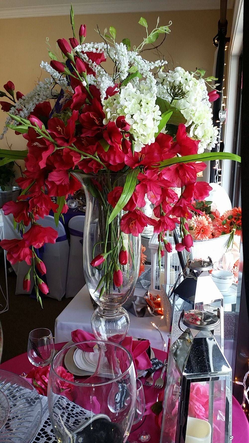 A vase filled with red and white flowers is on a table.