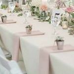 A long table with a pink table runner and flowers on it.