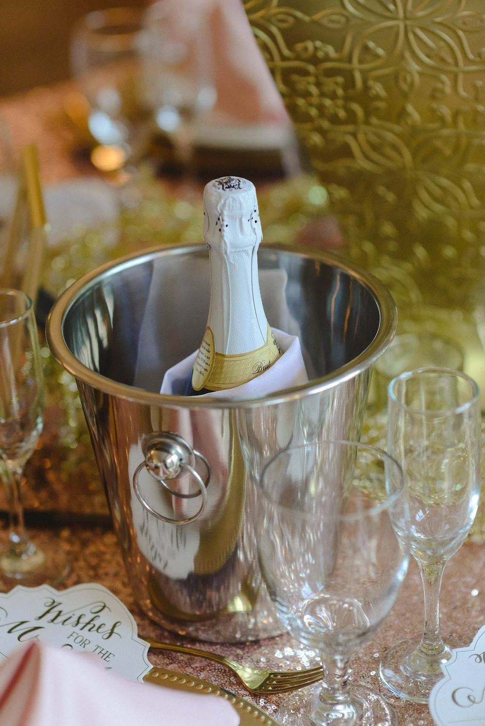 A bottle of champagne is in a bucket on a table.