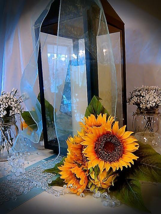A glass lantern with sunflowers in front of it