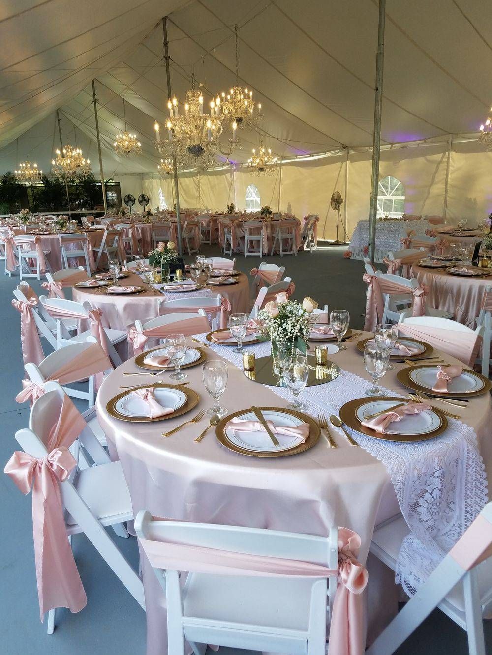 A large tent with tables and chairs set up for a wedding reception.