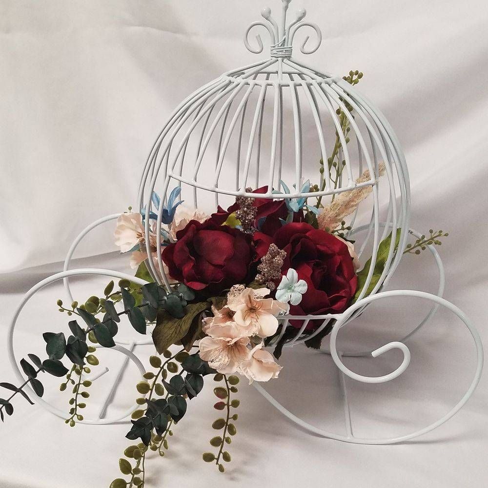 A white bird cage filled with flowers on a table
