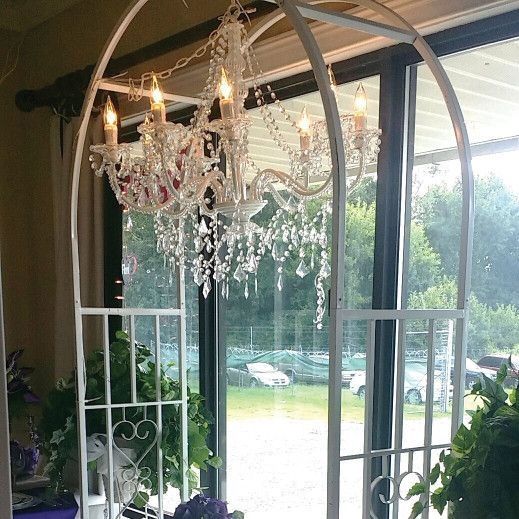 A chandelier is hanging from the ceiling in a room next to a window.