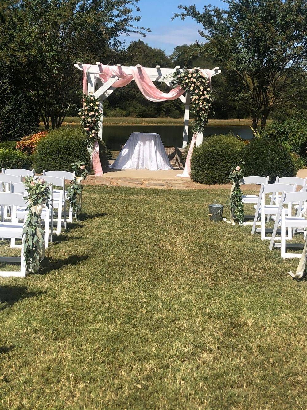 A wedding ceremony is taking place in the middle of a lush green field.