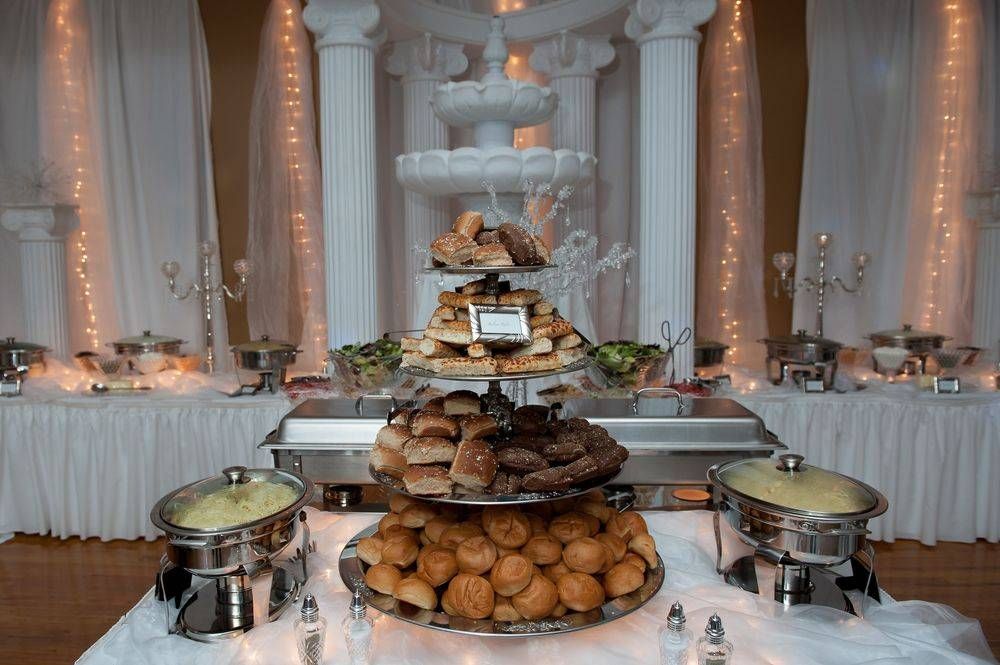 A buffet table with lots of food on it and a fountain in the background.