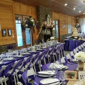 A long table with purple tables and chairs set up for a wedding reception.