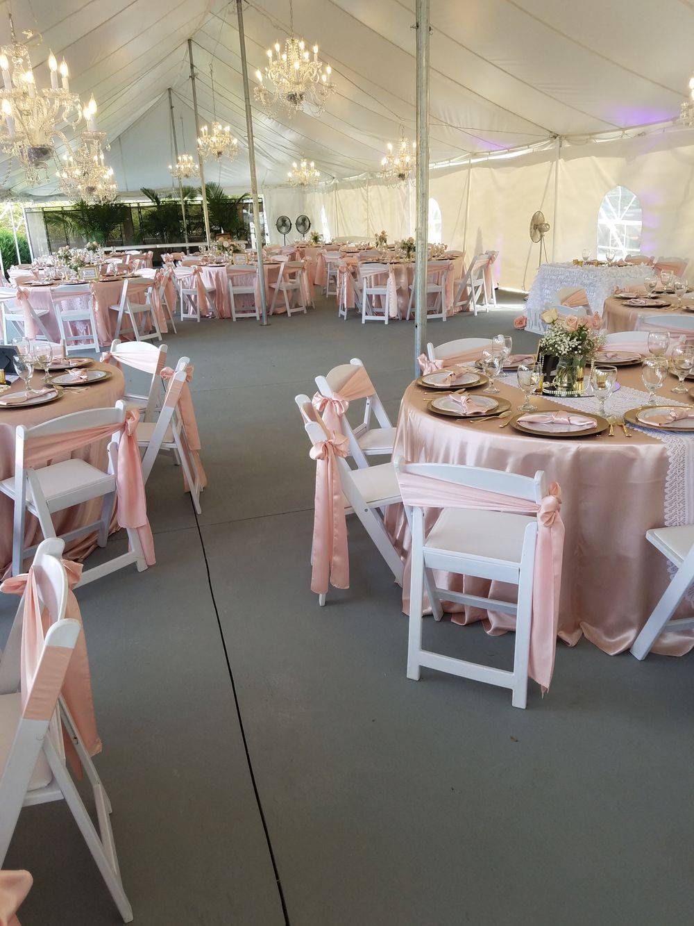 A large tent with tables and chairs set up for a wedding reception.