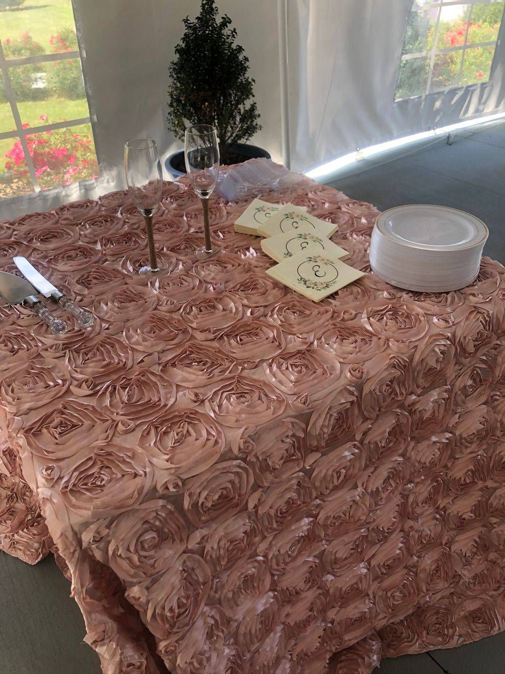 A table with a pink tablecloth and plates and glasses on it.