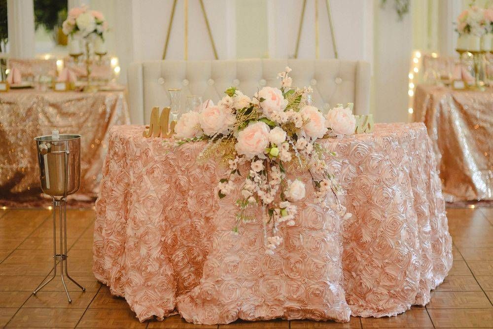 A table with a pink tablecloth and flowers on it.