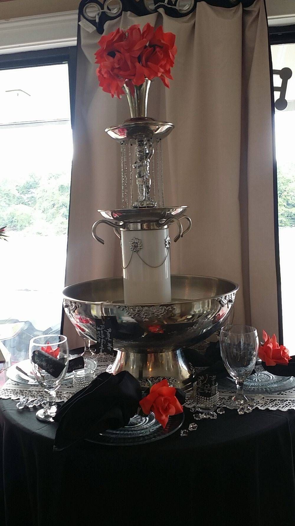 A fountain with flowers in it is sitting on top of a table.