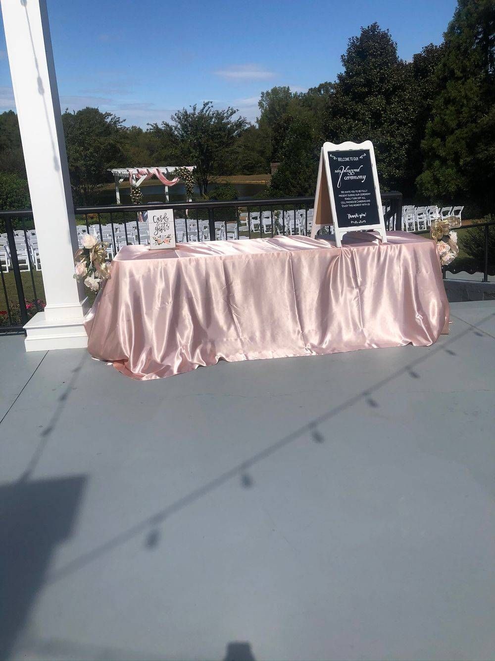 A table with a pink tablecloth and a sign on it is on a balcony.