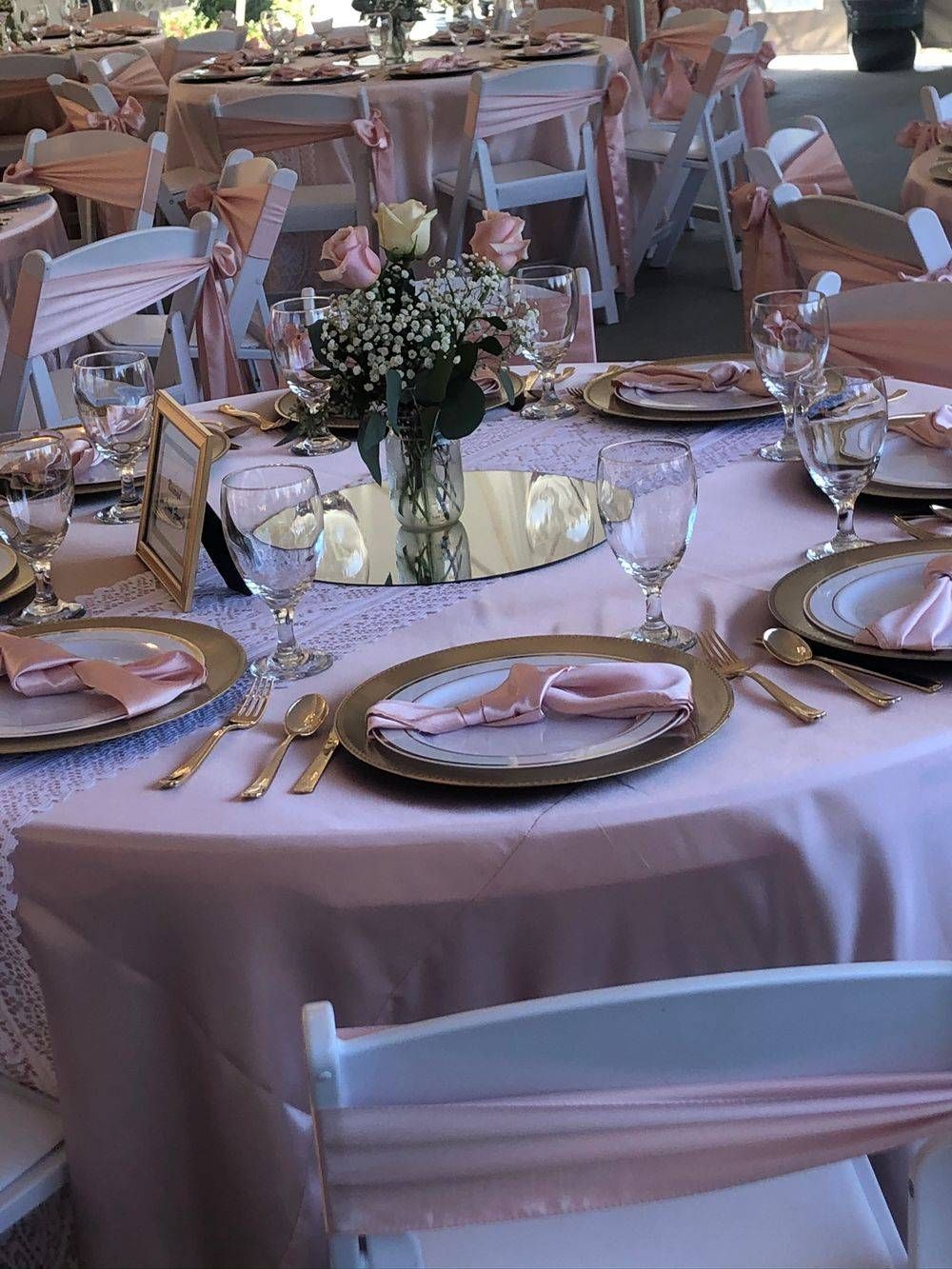A table set for a wedding reception with plates , utensils , and flowers on it.