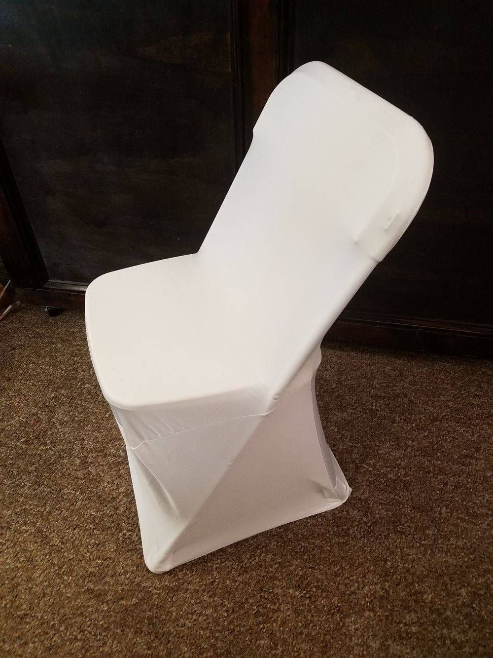 A white chair with a white cover is sitting on a carpet.