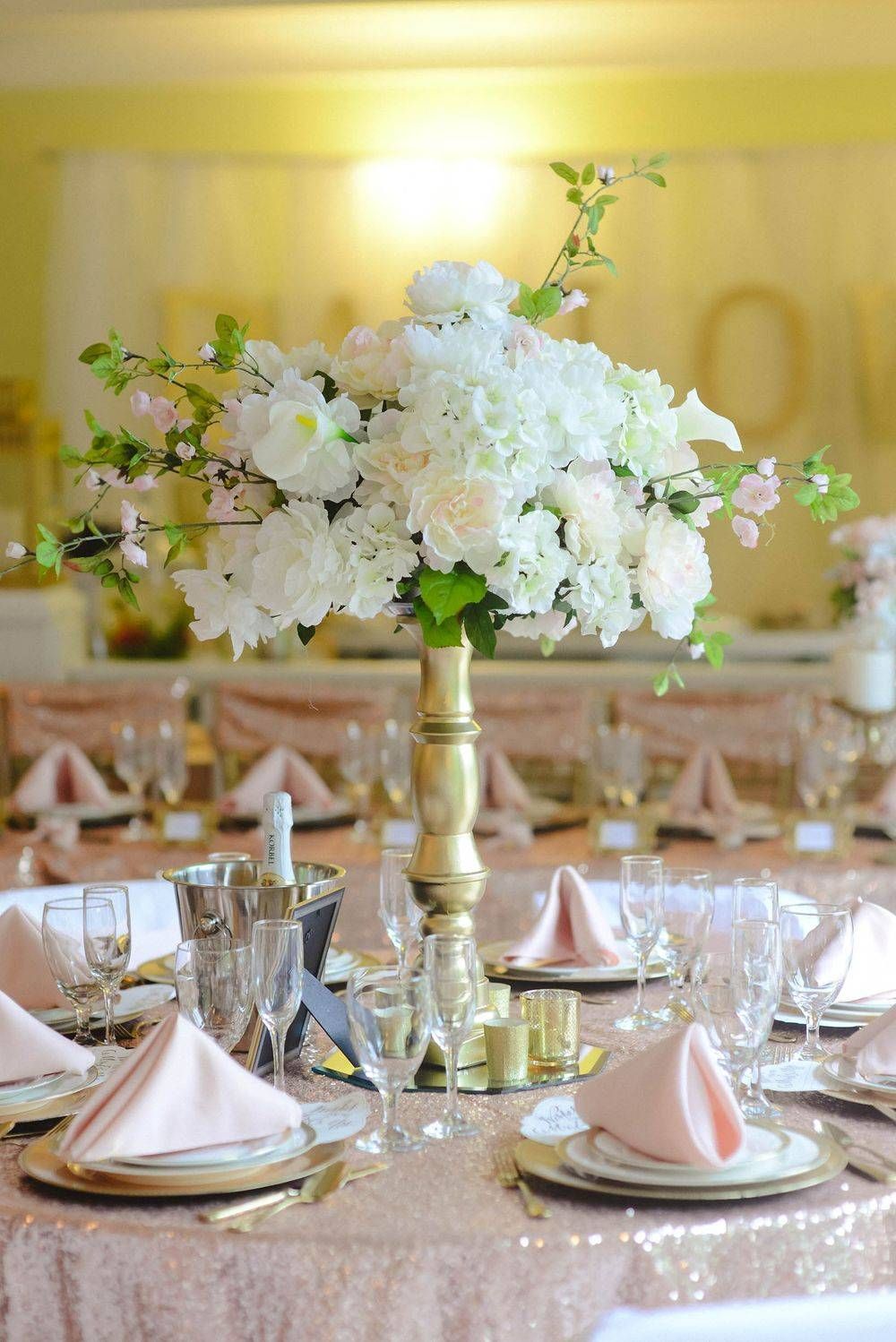 A table set for a wedding reception with a vase of flowers on it.