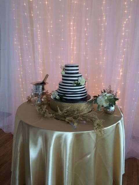 A wedding cake is sitting on a table with a gold tablecloth.