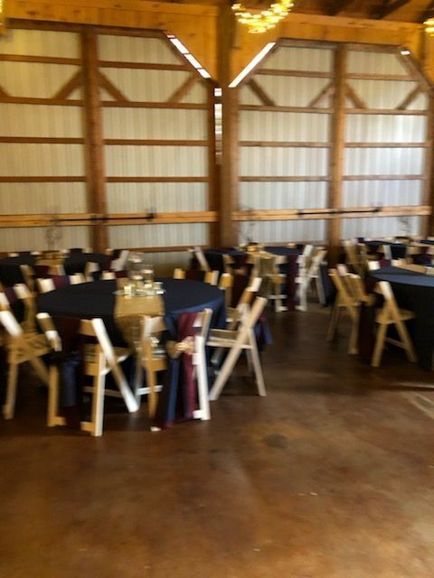 A large room with tables and chairs set up for a wedding reception.