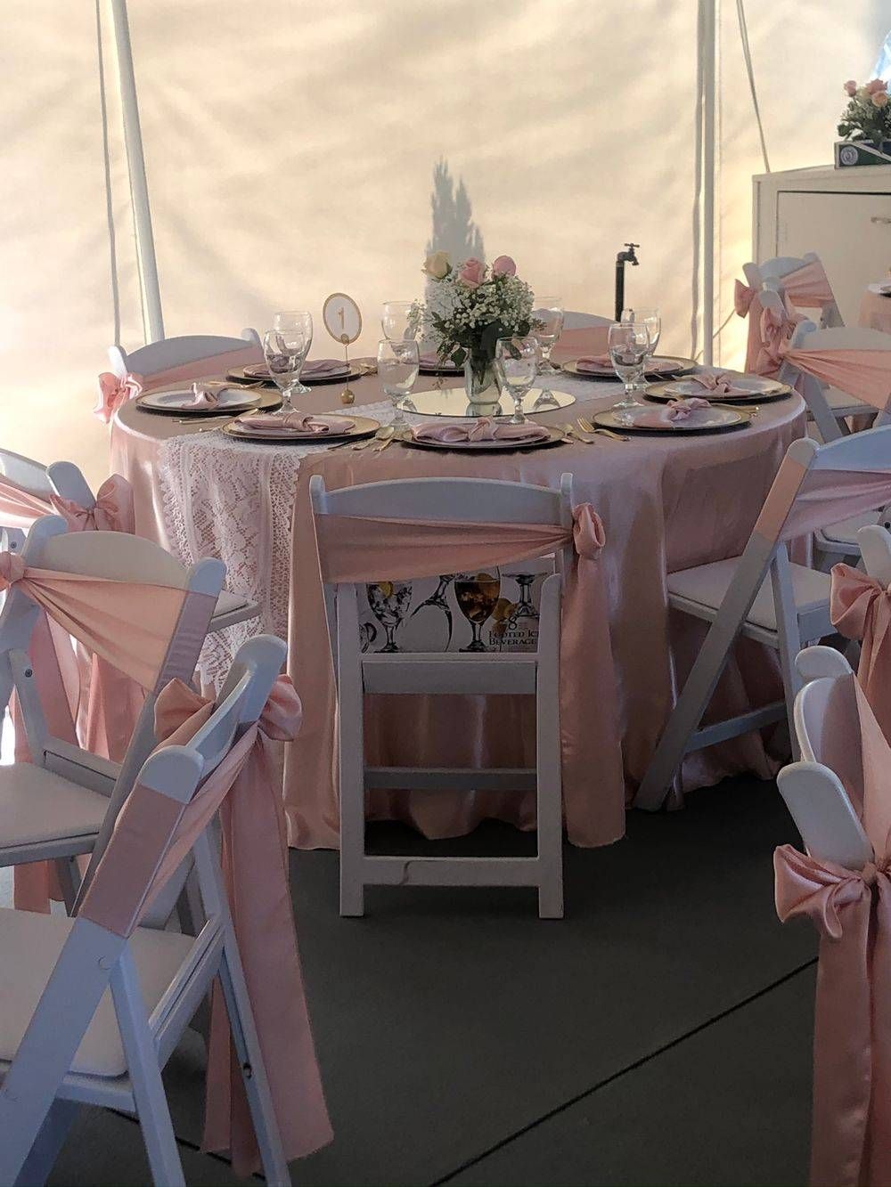 A table and chairs are set up under a tent for a wedding reception.