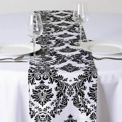 A table with plates and wine glasses and a black and white table runner