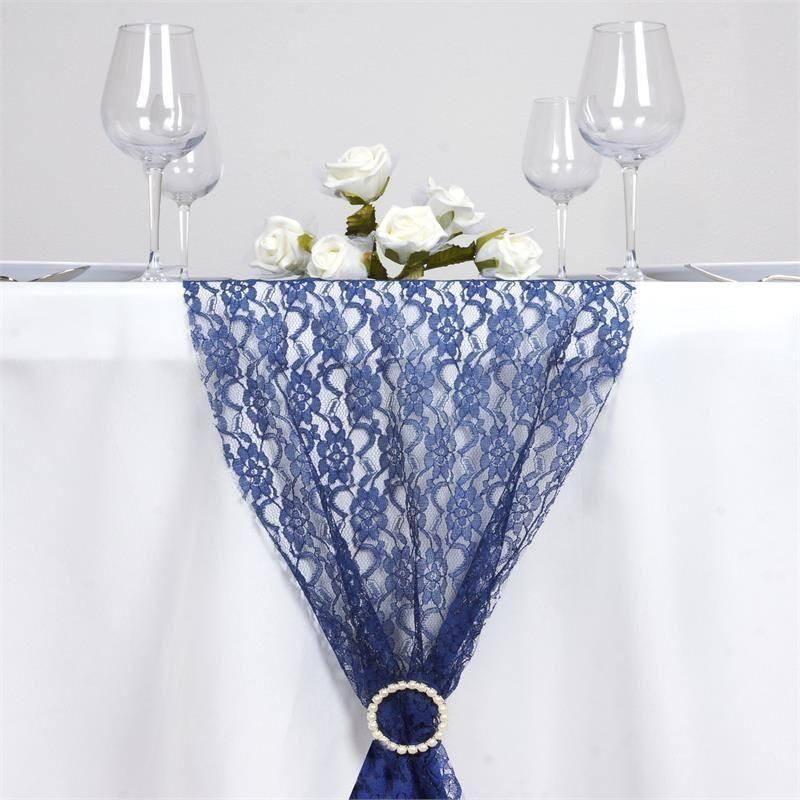 A table with a blue lace table runner and wine glasses