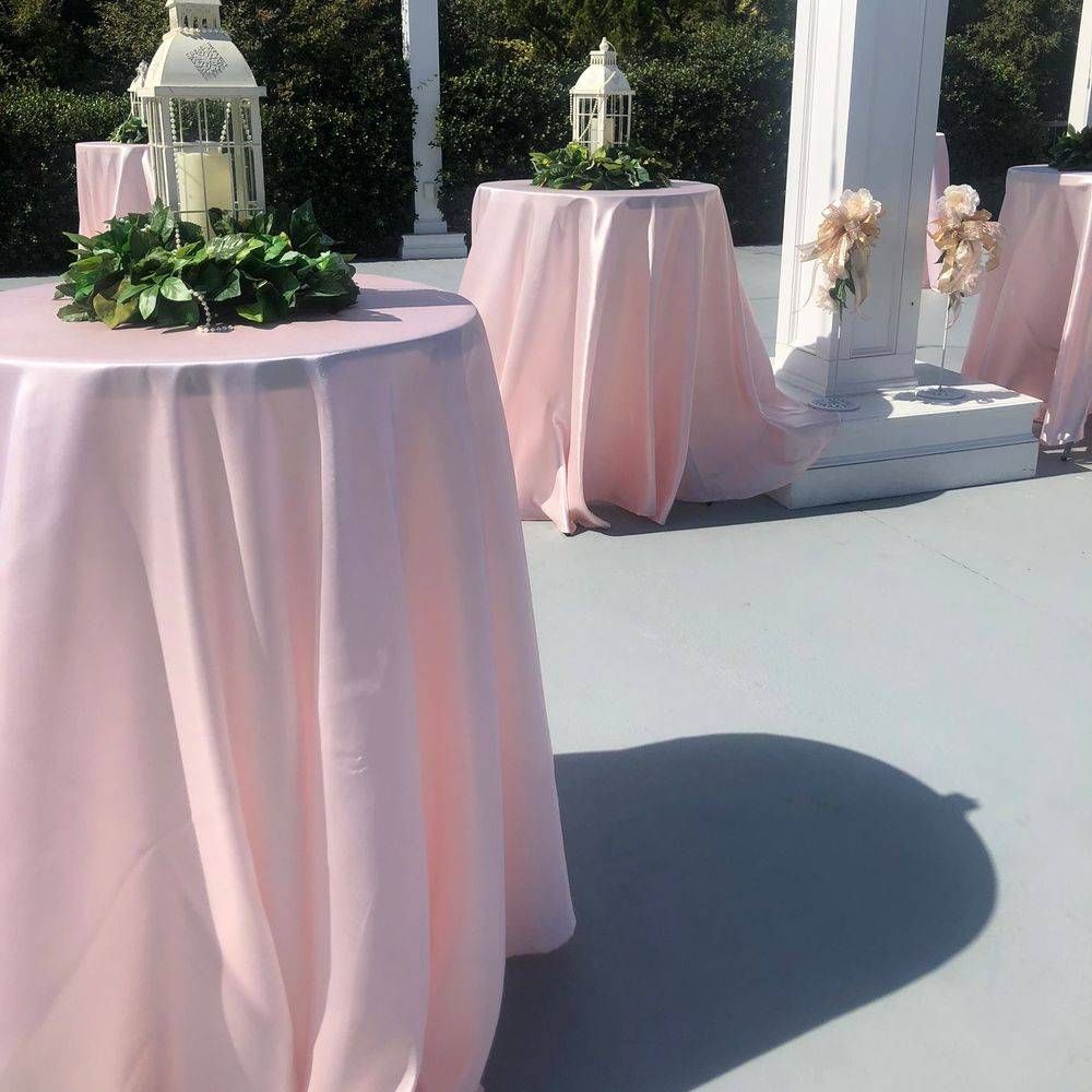 A row of pink tables with lanterns and flowers on them