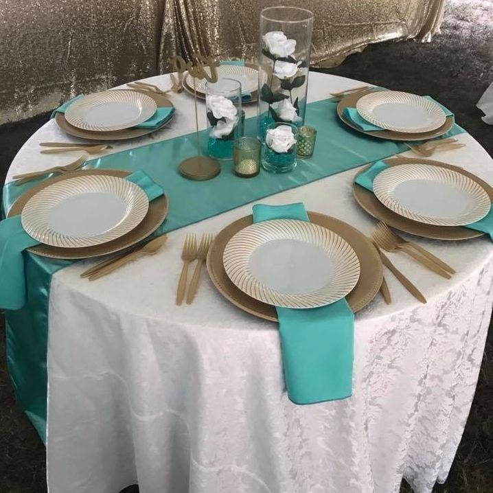 A table with plates and silverware and a turquoise table runner