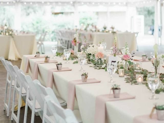 A long table set up for a wedding reception under a tent.