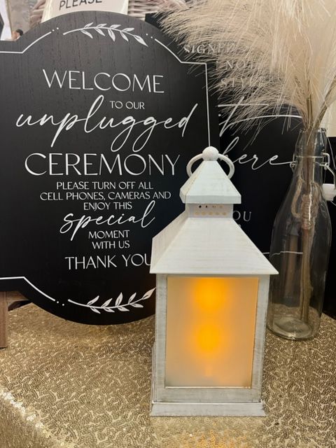 A white lantern is sitting in front of a sign that says welcome to our unplugged ceremony