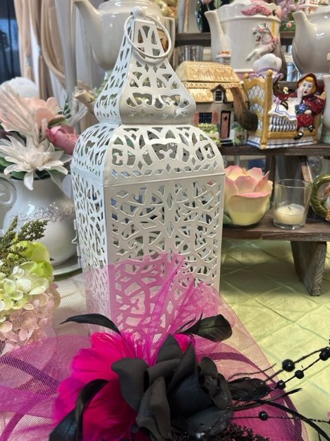 A white lantern with a pink flower on top of it
