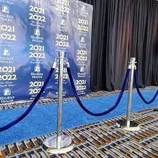 A blue rope barrier is sitting in front of a blue backdrop.