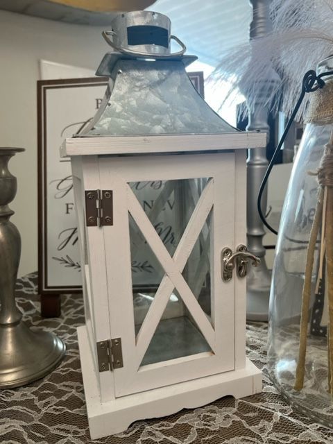 A white lantern sits on a table next to a lamp