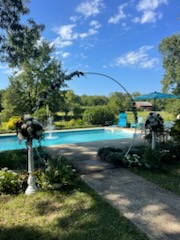 There is a swimming pool in the backyard with a fountain.