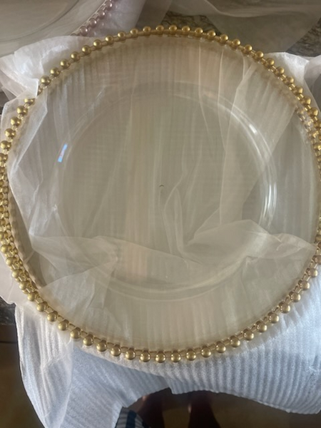 A clear plate with gold beads around it is sitting on a table.