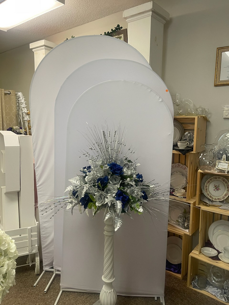 A vase of flowers is sitting in front of a white arch in a room.