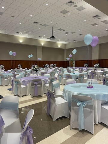 A large room filled with tables and chairs and balloons.