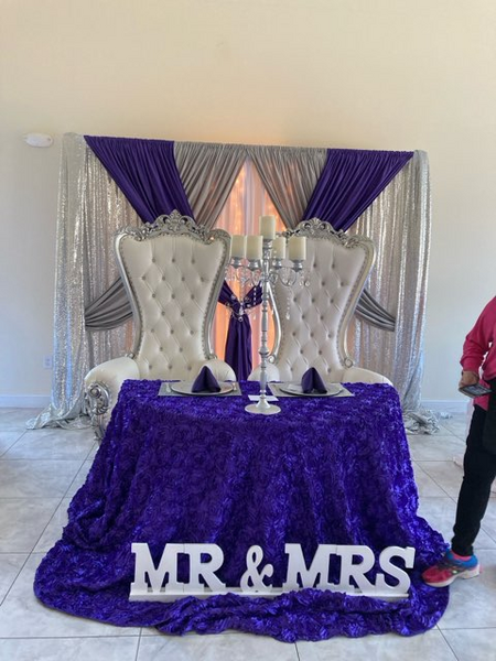 A table with a purple tablecloth and a sign that says mr and mrs