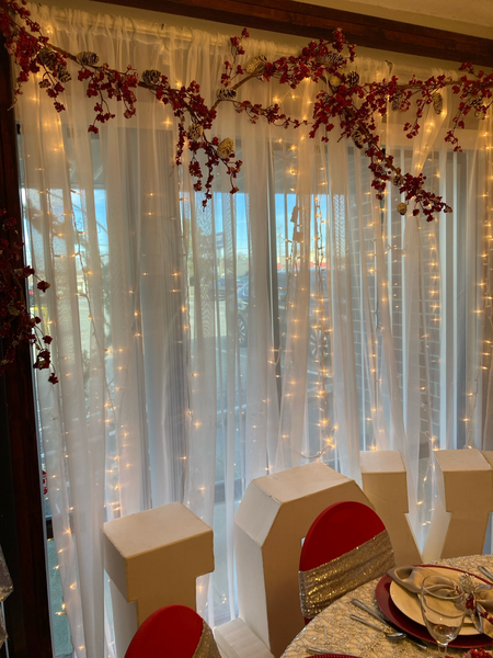 A room with a table and chairs and a white curtain with lights on it